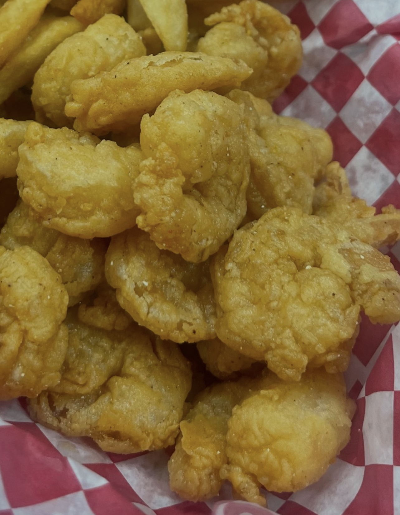 Golden fried shrimp piled high in a red checkered basket