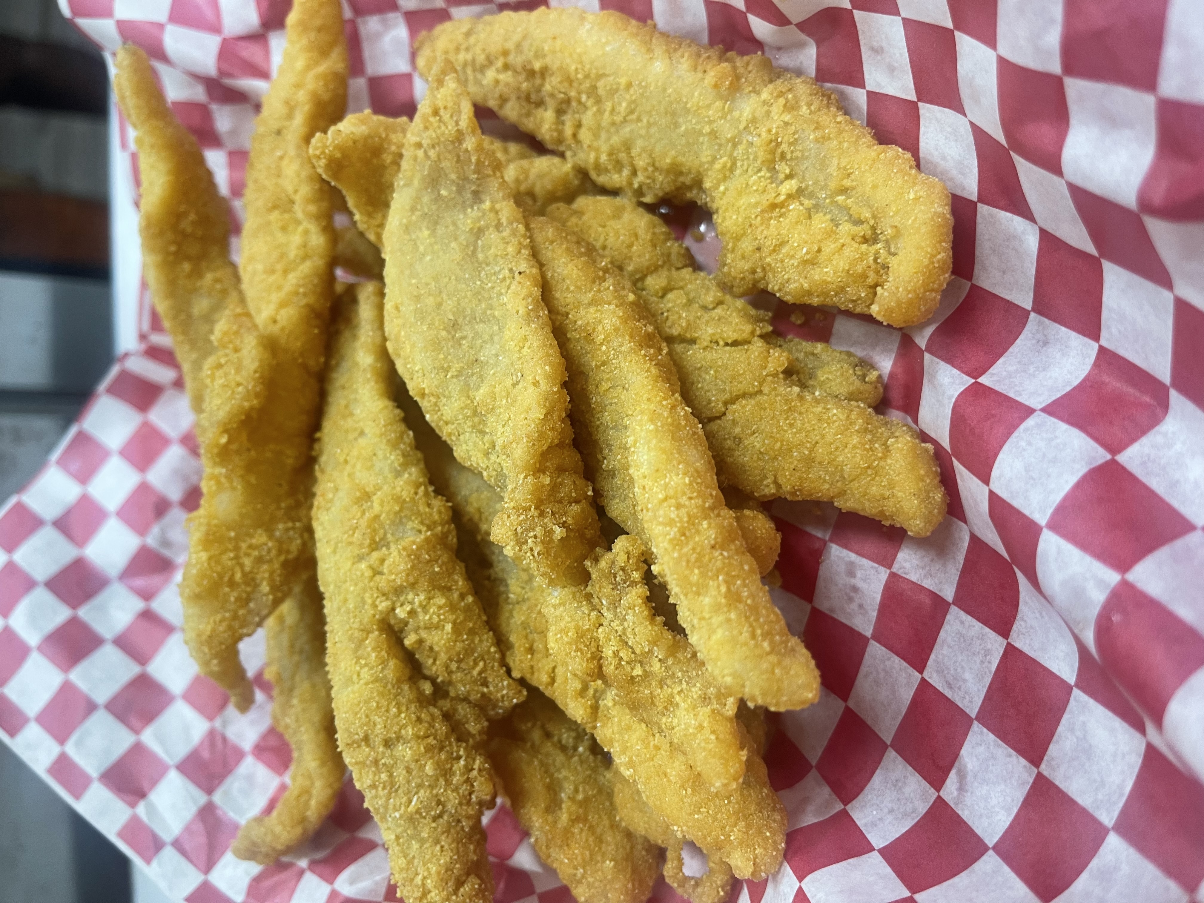 Fried catfish fillets in a red checkered basket