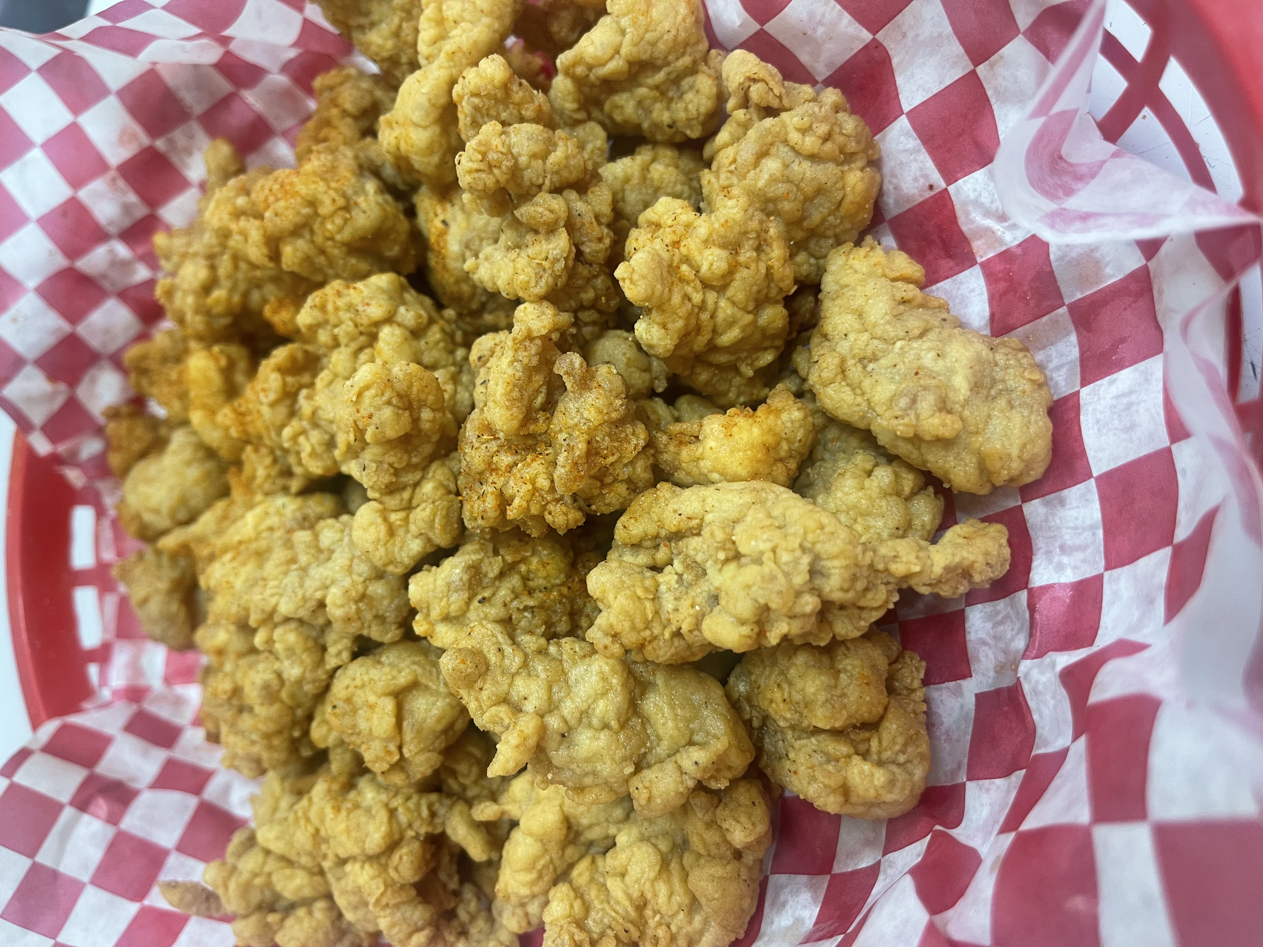 Fried alligator bites in a red basket with checkered paper